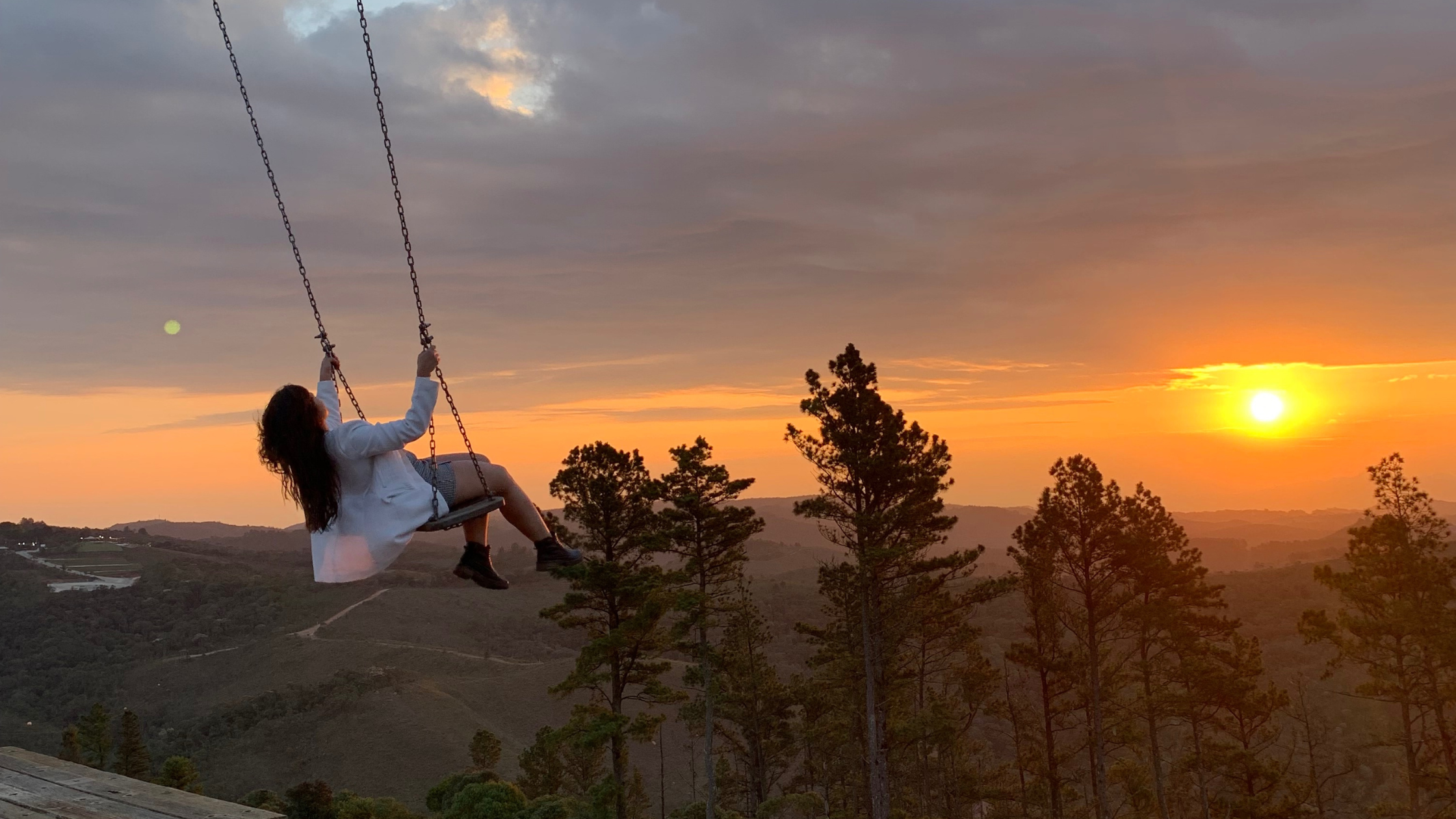 Uma mulher em uma balanço no pôr do sol